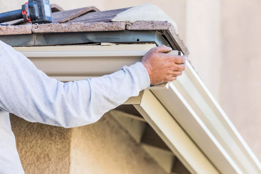 Close-up of new aluminum gutters being secured to a fascia board